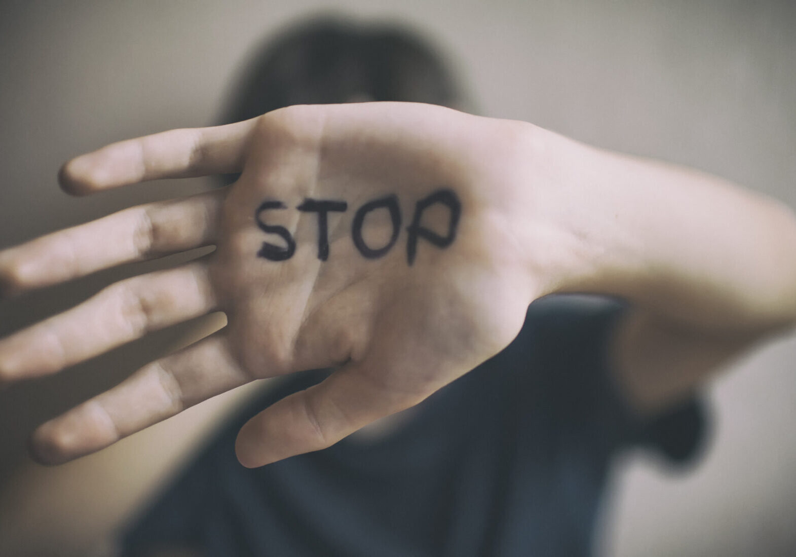 A 18-year-old guy protects himself with his hand with the inscription Stop isolated